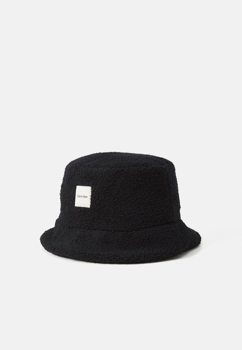 Chapeau bob en polaire noire avec un patch rectangulaire blanc du logo Calvin Klein à l'avant.