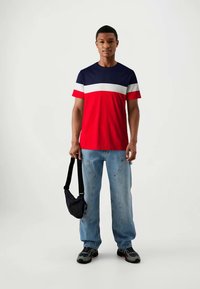 Rød, marineblå og hvid farveblokeret t-shirt med korte ærmer; båret med lyseblå løse jeans og en lille sort crossover taske.