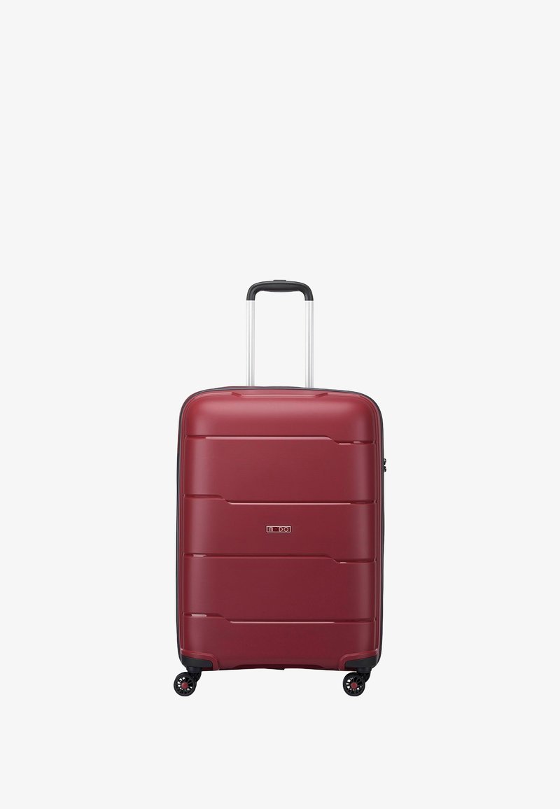 Maleta roja rígida con surcos horizontales, acentos negros, asa retráctil y cuatro ruedas para movilidad. Diseño compacto y textura suave.