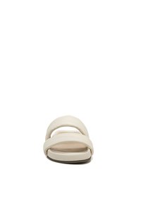 Light beige slide sandal featuring wide cross straps, a smooth leather-like texture, a flat sole, and a minimalist design.