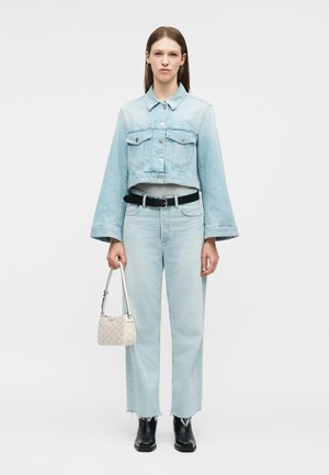 Moteris dėvi šviesiai mėlyną trumpą džinsinę džinsinę striukę ir derančias džinsines kelnes, juodą diržą, juodus kulkšnies ilgio batus, dešinėje rankoje laikydama mažą smėlio spalvos rankinę.