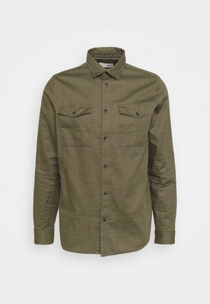 Olivno zelena majica s dugim rukavima, izdelana iz teksturirane tkanine, z dvema žepoma na prsih, zapiranjem na gumbe in tradicionalnim ovratnikom.