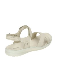 Sandal beige chiaro con design a cinghia incrociata, dotato di una morbida tomaia in pelle e di una suola traslucida flessibile. Inclusa anche una cinghia posteriore regolabile.