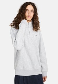 Lichtgrijze kwartrits sweatshirt van een zachte, gestructureerde stof. Kenmerkend zijn de ribbelmanchetten en een logo-accent op de borst.