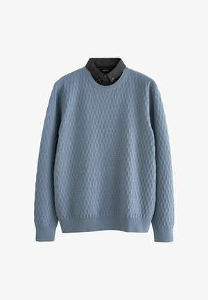 Pulover tricotat de culoare albastru deschis, cu un model texturat în grilă, guler rotund și manșete cu nervuri. Purtați peste o cămașă închisă cu guler.