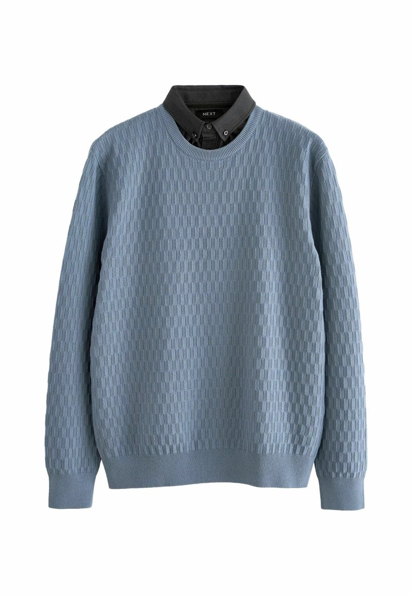 Un pull en maille bleu clair avec un motif en grille texturé, un col rond et des poignets côtelés. Superposé à une chemise à col sombre.
