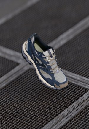 Sporty sneaker featuring a mix of tan and navy mesh and synthetic materials, textured outsole, and grey laces with minimal branding.