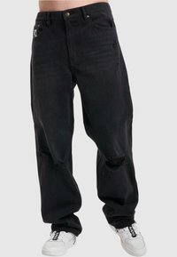 Jeans de mezclilla negra con un corte relajado, que presentan desgastes en las rodillas, diseño de cinco bolsillos y detalles en dorado.