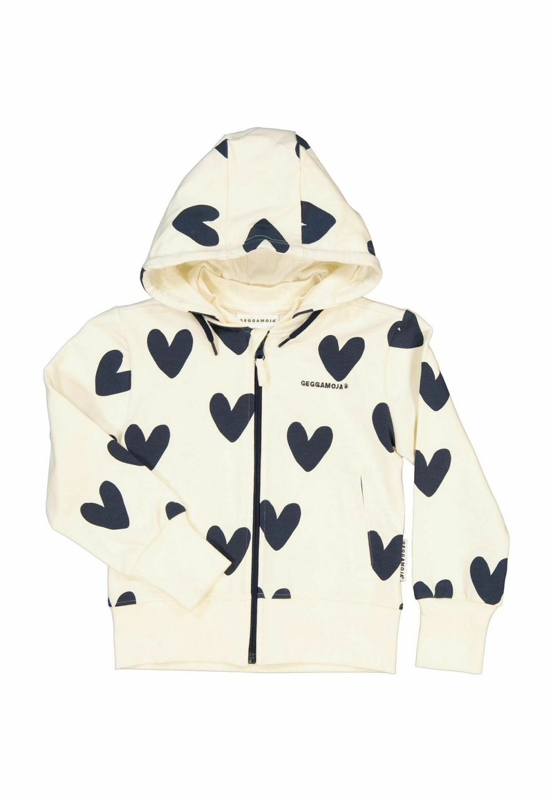 Zip hoodie, krämfärgad tyg med stora marinblå hjärtmönster, långa ärmar, framfickor och en huva med dragsko. Märkesetikett synlig på insidan.