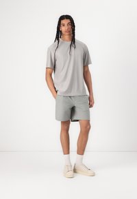 Grå ribbet t-shirt med korte ærmer og matchende grå shorts. Et par lysfarvede sneakers og hvide sokker i ankellængde.