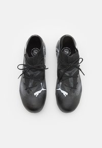 Scarpe sportive nere con tomaia texturizzata, dotate di collare in maglia, lacci neri e marchio bianco. Design elegante e a profilo basso.
