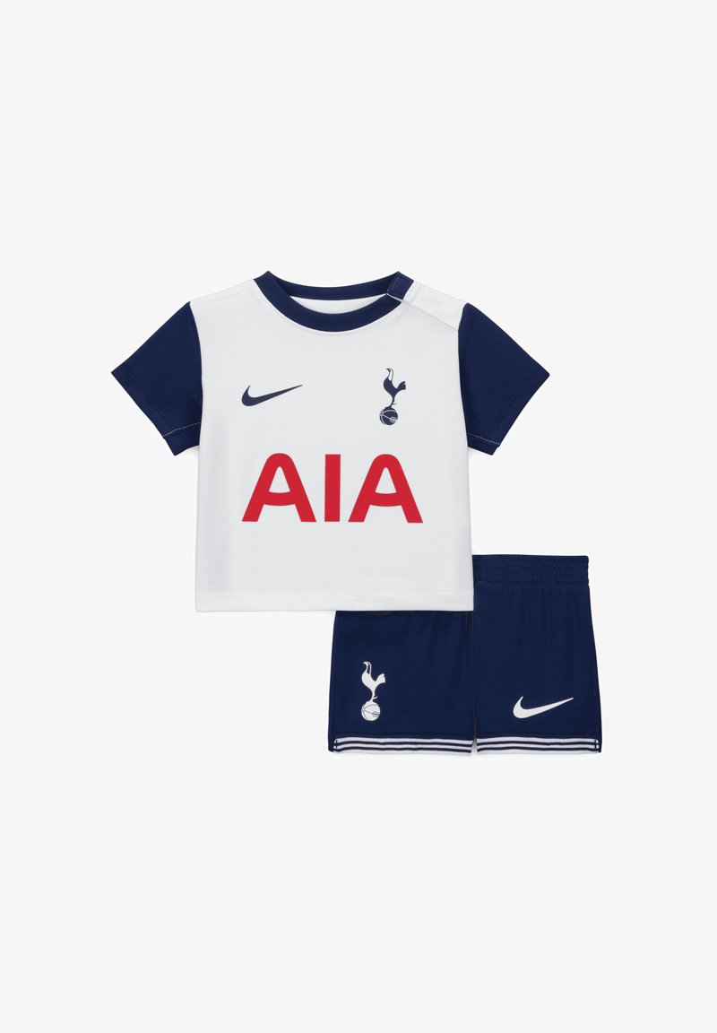 Chemise blanche avec des manches bleu marine, arborant "AIA" en rouge et un logo. Shorts bleu marine assortis avec des accents blancs et le logo, fabriqués en tissu respirant.