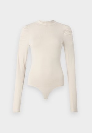 Body a maniche lunghe in beige chiaro, realizzato in tessuto liscio. Presenta un collo alto e dettagli arricciati alle cuciture delle spalle.