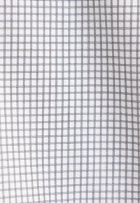 Tissu blanc avec un motif en grille composé de fines lignes noires régulièrement espacées formant de petits carrés.