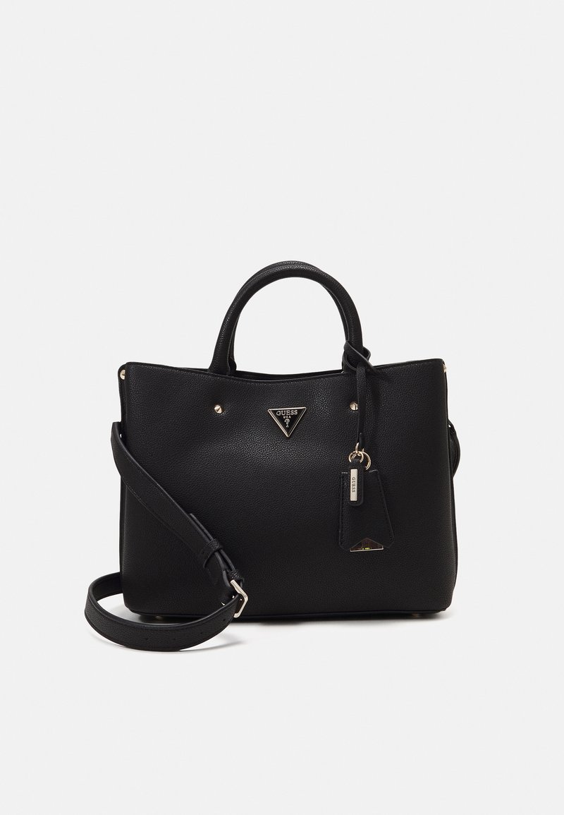 Sac à main en cuir noir Guess avec double poignée, bandoulière ajustable et logo métallique triangulaire à l'avant sur un fond uni.