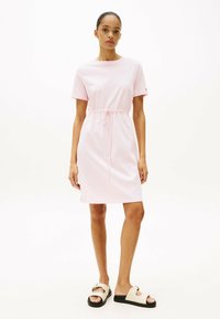 Roze katoenen jurk met korte mouwen, een cinched taille en een knielange snit. Draag het met beige sandalen met zwarte zolen en gouden accenten.