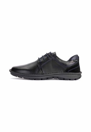 Chaussure décontractée pour homme en cuir noir avec des surpiqûres bleu foncé, fermeture à lacets et semelle en caoutchouc texturée sur fond blanc.