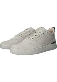 Paire de baskets basses gris clair avec des panneaux en daim et cuir, fermeture à lacets à l’avant, et semelles en caoutchouc blanches texturées.