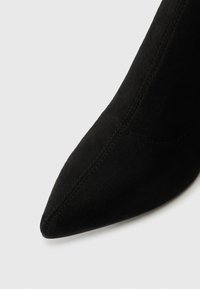 Mustast nubukist teravatepid kõrvitsad nähtava õmblusdetailiga valgel taustal.