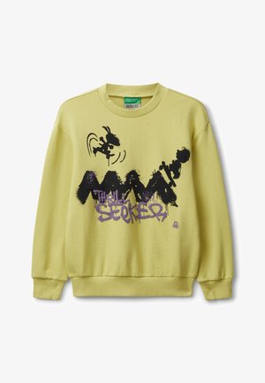 Sweatshirt jaune clair avec un imprimé graphique présentant des designs noirs et violets et le texte "Thrill Seeker." Poignets et ourlet côtelés.