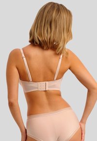 Nude beha met verstelbare bandjes en een haak-en-oogsluiting. Gladde textuur, minimalistisch ontwerp en naadloze randen. Gecombineerd met bijpassende slip.