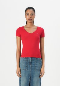 T-shirt rouge à col en V à manches courtes, réalisé en coton doux, avec une coupe ajustée et un petit logo sur la poitrine.