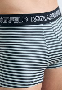 Črne in svetlo modre črtaste bokserice z črnim elastičnim pasom, na katerem je v beli barvi napis "KARL LAGERFELD". Mehka tkanina.