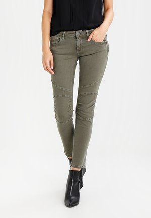 Olijfgroene jeans met een slim fit, voorzien van textuurdetails en stikaccenten. Gepaald met zwarte enkellaarsjes.