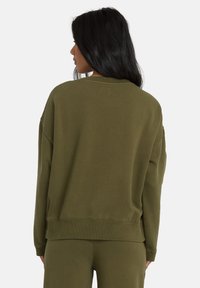 Felpa verde oliva con una vestibilità comoda, polsini a costine e collo a giro. Tessuto morbido con cuciture minime, mostrata da dietro.