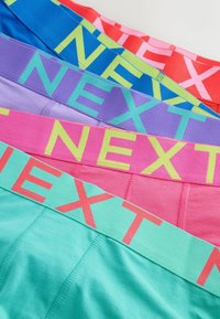 Barevné bavlněné boxerky jsou naskládány, mají široké elastické pasy s logem "NEXT" v kontrastních odstínech růžové, modré, zelené a fialové.