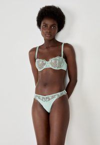 Mintgrünes Unterwäsche-Set mit floralen Spitzenakzenten, einem Balconette-BH mit verstellbaren Trägern und einem passenden Tanga mit gewellten Kanten.