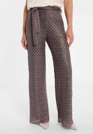 Weit geschnittene Häkelnieten in Mauve mit gebundenem Taillengürtel, getragen mit hellrosa spitzen Schuhen und einer in die Hose gesteckten weißen Bluse.