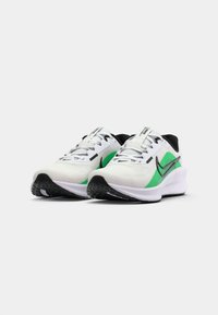 White athletic shoes with green accents, black detailing, mesh upper, reflective laces, and textured black outsole.