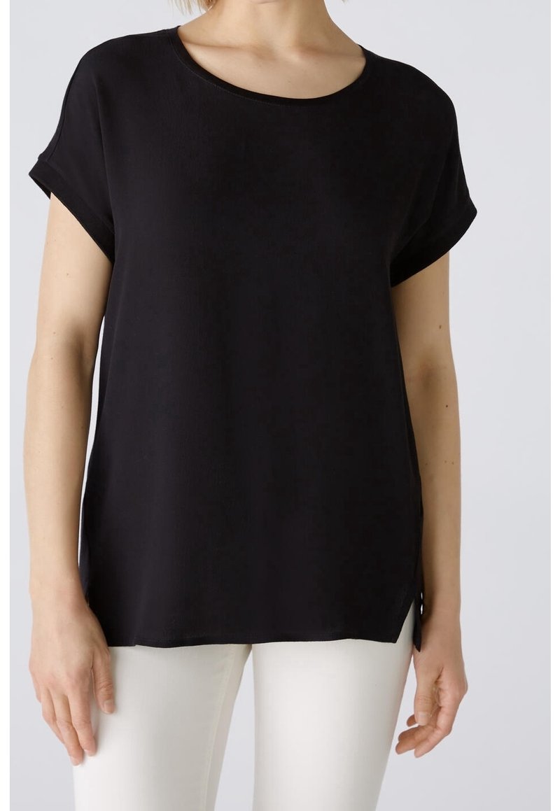 Top nero a maniche corte con scollatura rotonda, texture morbida e rifiniture arrotolate, dotato di spacco laterale per un fitting rilassato.