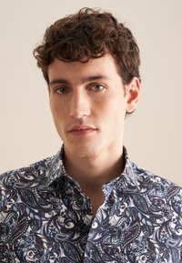 Camicia a maniche lunghe con motivo paisley scuro in tonalità navy, bianco e bordeaux; tessuto in cotone; colletto con bottoni; dettaglio della patta frontale.