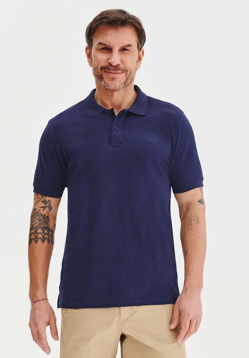 Granatowa koszulka polo z miękkiego materiału, z krótkimi rękawami, klasycznym kołnierzykiem i dwoma guzikami. Posiada subtelne logo.