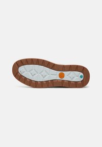 Suela de goma con un diseño marrón y blanco, texturizada para ofrecer agarre. Presenta un logo circular naranja y un acento azul cerca del talón.