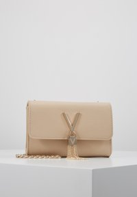 Beige synthetisch leren handtas met een klep, gouden V-vormige hardware en een kettingfranje detail. Voorzien van een afneembare kettingriem.