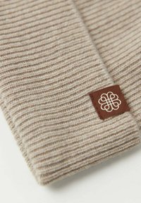 Brun vävd ribbstickad halsduk med en mjuk textur och en brun läderetikett med ett vitt emblem.