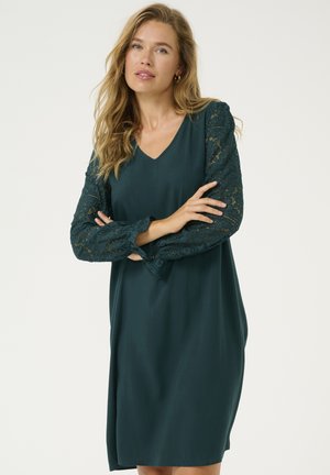 Teal dress with a V-neck and long lace sleeves. Smooth fabric with a loose fit, featuring lace accents on sleeves and a simple design.