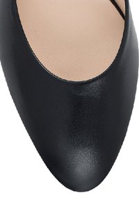 Chaussure plate en cuir noir avec bout arrondi et doublure intérieure beige, présentée sur fond blanc.
