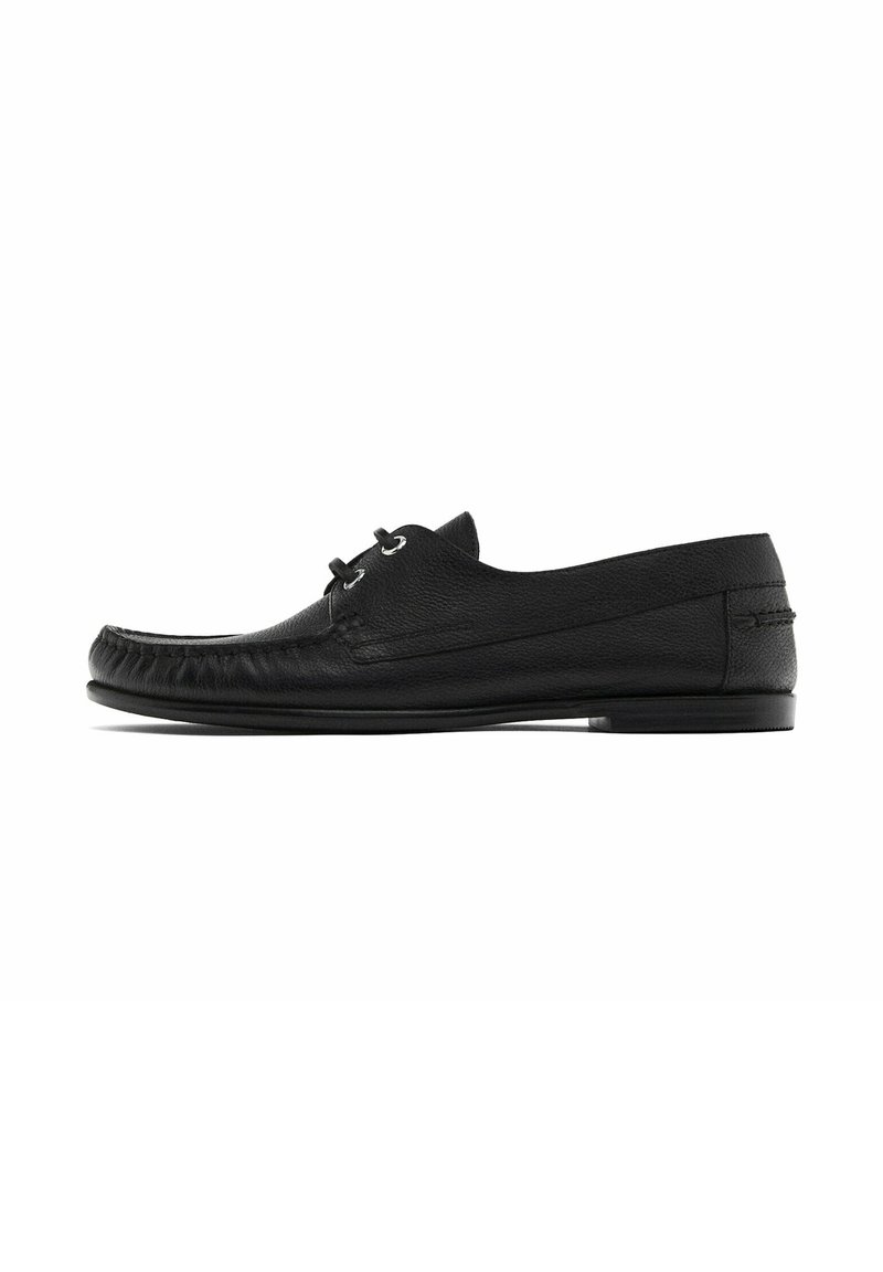 Mocassin pour homme en cuir noir avec détails de couture et laçage à l'avant, semelle plate, photographié sur fond blanc.