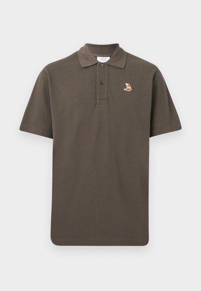 Καφέ κοντομάνικο πόλο μπλουζάκι με γιακά, δύο κουμπιά και μικρό κεντητό λογότυπο αλεπούς στο αριστερό στήθος.