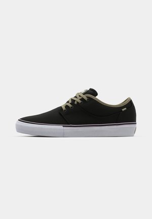 Black canvas sneakers with a low-profile design, contrasting grey laces, white rubber sole, and a subtle purple accent along the midsole.