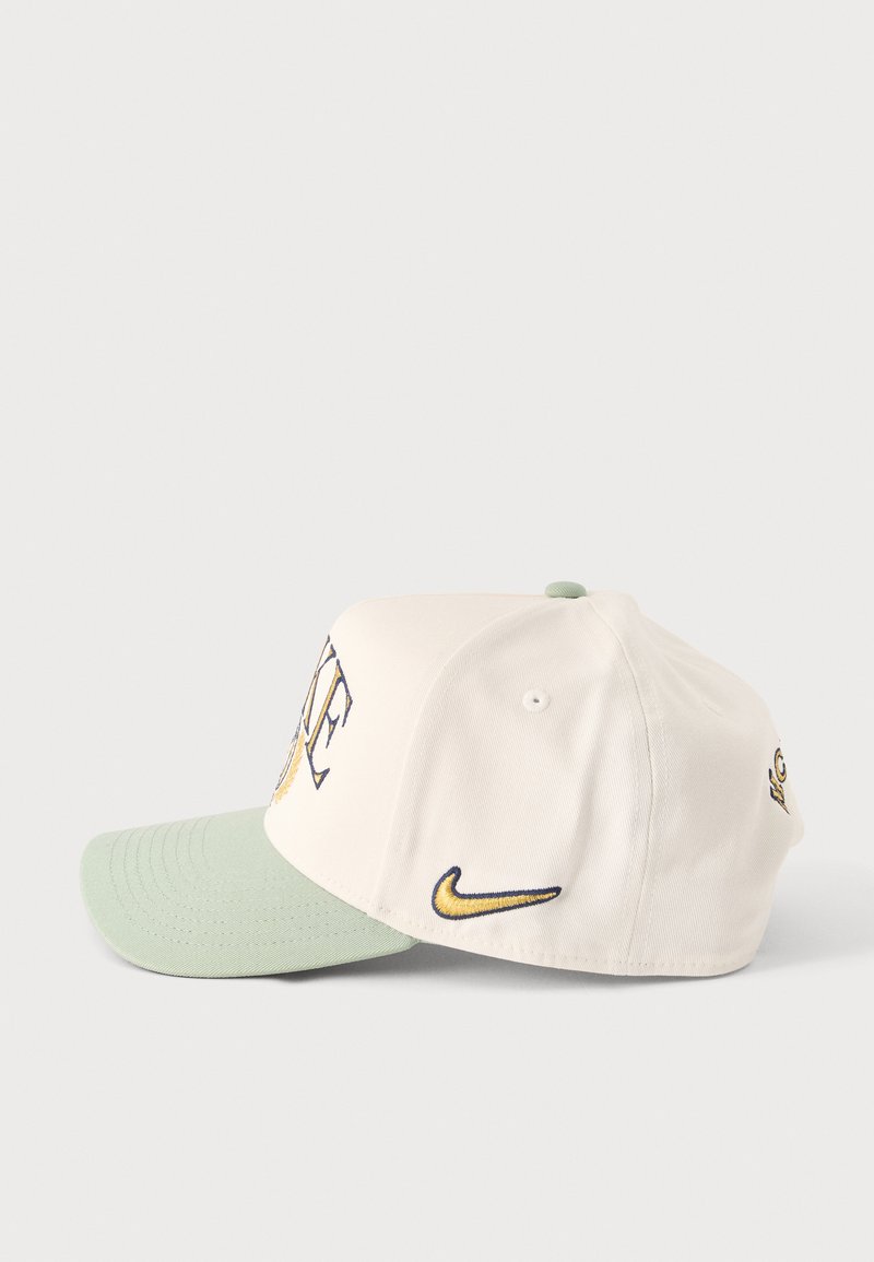 Gorra blanca con visera verde claro, logo Nike en azul marino y dorado en el lateral y letras parciales "LA" en el panel frontal.