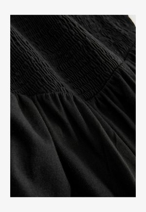 Schwarzes Kleid mit strukturierter Stoffqualität, einem gerafften Oberteil und einem gesammelten Rock, das Kontraste in Mustern und glatter Textur hervorhebt.