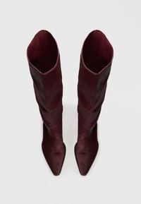 Bottes bordeaux montantes avec un bout pointu, en cuir lisse, au design élégant et ajusté avec une texture douce.