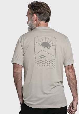 Beige T-Shirt mit kurzen Ärmeln, das hinten ein graues Grafikdesign mit einer Sonne, Bergen und einem Fahrrad zeigt, umgeben von wellenförmigen Linien am unteren Rand.