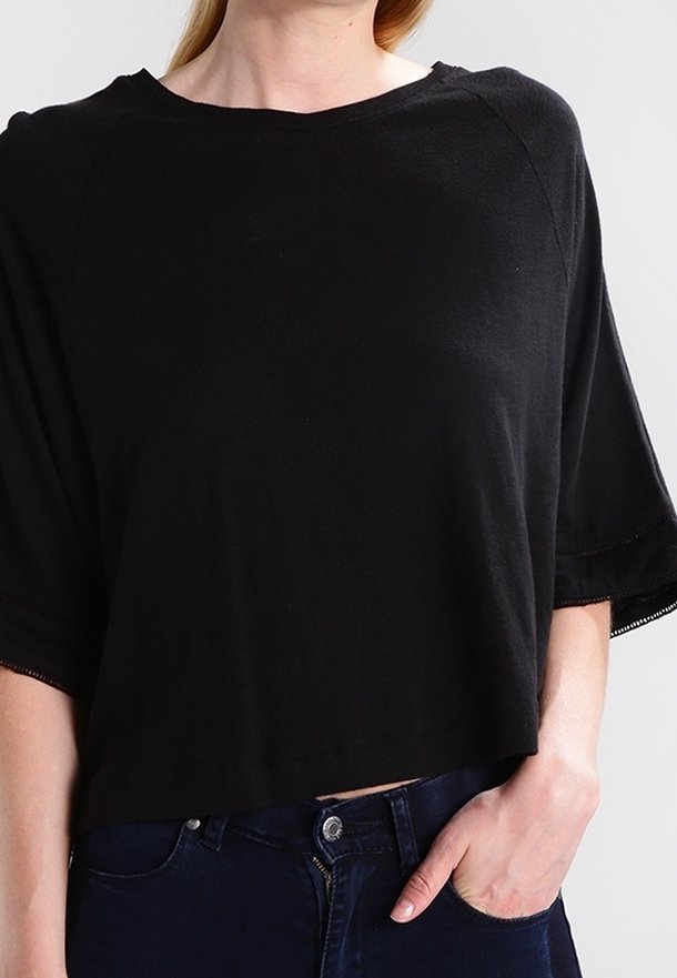 Svart kortärmad t-shirt i mjukt tyg, med en bred halsringning och lösa ärmar samt avslappnad passform. Inga anmärkningsvärda mönster eller detaljer.