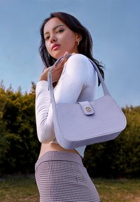 Sac à main lilas en cuir embossé crocodile, avec une forme structurée, une bandoulière simple et un rabat sur le devant avec une fermeture à bouton doré.